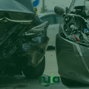 Two cars with severe rear and front-end damage after a collision, parked on a street with another vehicle in the background.