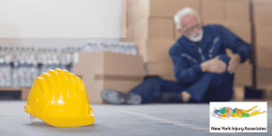 A yellow hard hat lies on the floor in the foreground; in the background, an older man in work clothes sits holding his leg in pain—reminding us of the importance of No Fault Insurance Doctors in Northampton for workplace injuries.