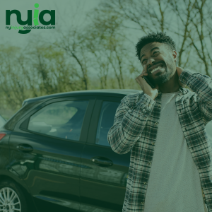 A man stands next to a car, holding his neck and grimacing in discomfort. The logo for NY Injury Associates appears in the top left corner, highlighting trusted injury doctors in Baldwin.
