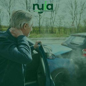 An older man holds his neck while standing beside a blue car involved in a rear-end collision, with visible smoke and another car behind him.