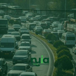 Traffic congestion on a multi-lane road with cars, buses, and trucks moving slowly in both directions; greenery separates the lanes, reminding drivers to stay alert and know where to find an Auto Accident Doctor in Huntington if needed.